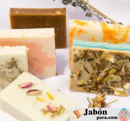 Fotografía de diferentes barras de jabón casero artesanal con ingredientes naturales, decoradas con hierbas y flores secas, en un ambiente luminoso y acogedor.