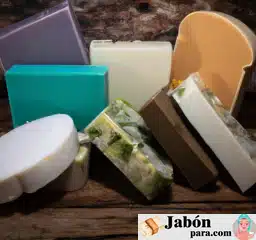 Fotografía de varias barras de jabón casero, con ingredientes naturales a la vista, sobre una superficie de madera rústica.